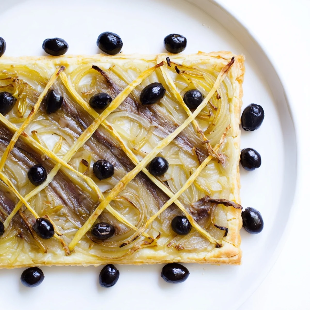 Golden-brown Classic Onion Pissaladière Tart, topped generously with olives and savory anchovies.