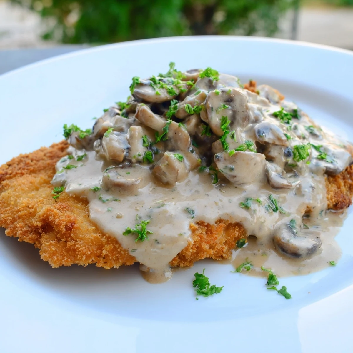 Crispy pork schnitzel under creamy mushroom gravy, a classic German Jaeger Schnitzel dinner.