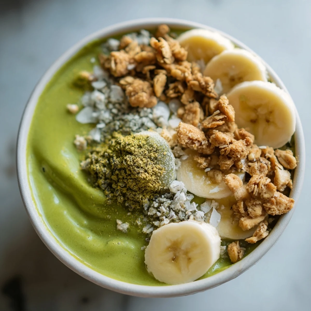 A vibrantly layered Gingerbread Cookie Matcha Breakfast Smoothie Bowl, topped with granola and candied ginger.