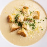This creamy garlic bread soup steams invitingly in a white bowl, promising warmth and rich flavors.