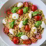 A refreshing bowl of Caprese Orzo Salad, showcasing tender pasta and fresh basil's bright flavors.