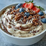 Creamy vanilla bean frappuccino smoothie bowl topped with crunchy granola and fresh berries, a delicious breakfast treat.  