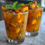 2. A tall glass of bubbly mango peach tea, garnished with ripe peach and mango wedges, perfect for hot afternoons.  