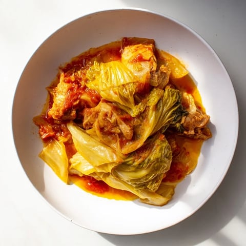 Sweet cabbage and pork stew simmering gently in a large pot, vegetables are visible and tender.