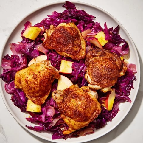 Golden, crispy Oktoberfest Chicken rests atop sweet red cabbage in a savory baked dish.