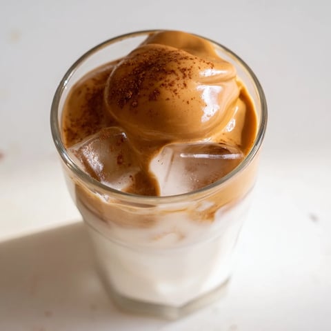 Fluffy brown sugar Dalgona latte, beautifully layered with whipped coffee, milk, and ice, ready to sip.