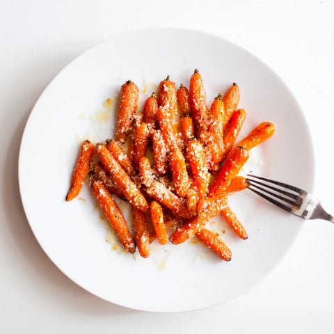 Golden roasted Parmesan baby carrot chips glistening with honey, caramelized edges, served warm in a rustic bowl.