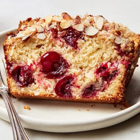 This golden Cherry Almond Loaf Cake is topped with sugared almonds, perfect with coffee.