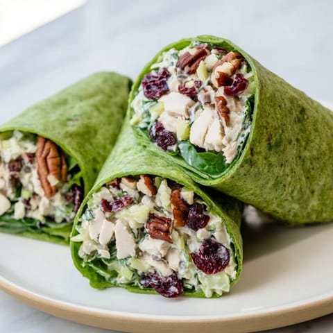 Close-up of a festive Cranberry Pecan Chicken Salad Christmas Wrap, ready to eat with fresh, green salad.