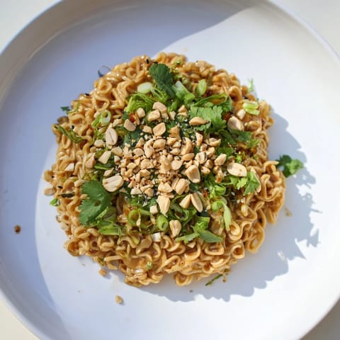 A close-up of finished Instant Peanut Thai Sauce Noodles, garnished with scallions and peanuts, delicious flavors.