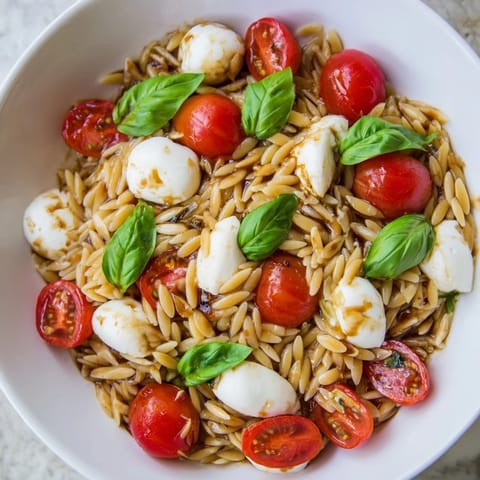 A refreshing bowl of Caprese Orzo Salad, showcasing tender pasta and fresh basil's bright flavors.