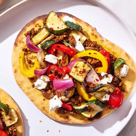 Flavorful naan bread pizza with a vibrant medley of roasted bell peppers and tangy olive tapenade.