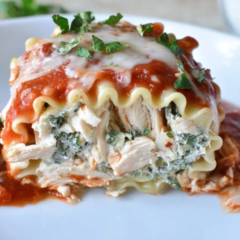 Twisted pasta noodles hold a savory chicken and spinach filling, topped with golden cheese and fresh parsley garnish.