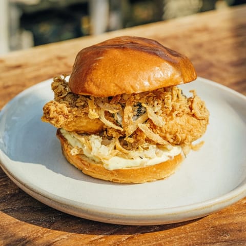 Crispy Onion Chicken Sandwich stacked with crunchy fried onions and lettuce.