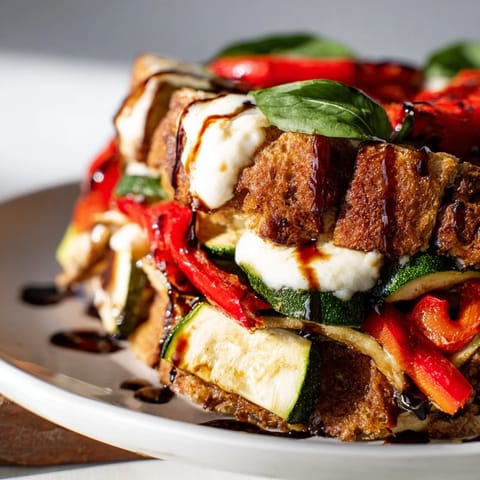 A close-up of Roasted Veggie Caprese Grilled Cheese with juicy tomatoes and fresh basil leaves.