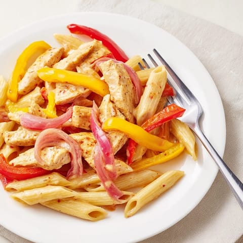 Creamy Cajun Chicken Pasta Lite with juicy chicken strips and al dente penne in a spicy, reduced-fat sauce, garnished with parsley.