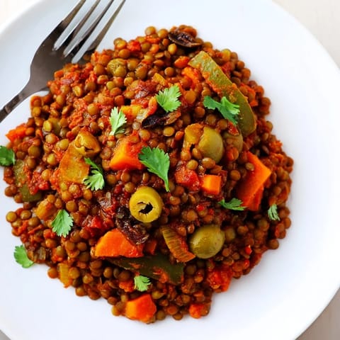 The vibrant, plant-based Cuban-Inspired Lentil Picadillo served in a white bowl with fluffy white rice.