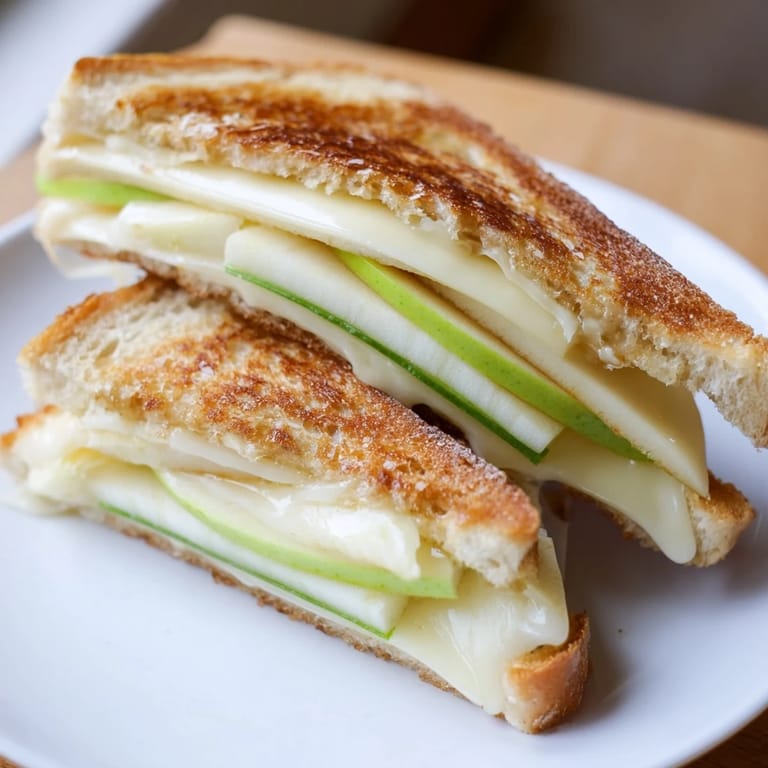 Sizzling Brie and apple grilled cheese, a gourmet sandwich ready to enjoy with a glass of wine.