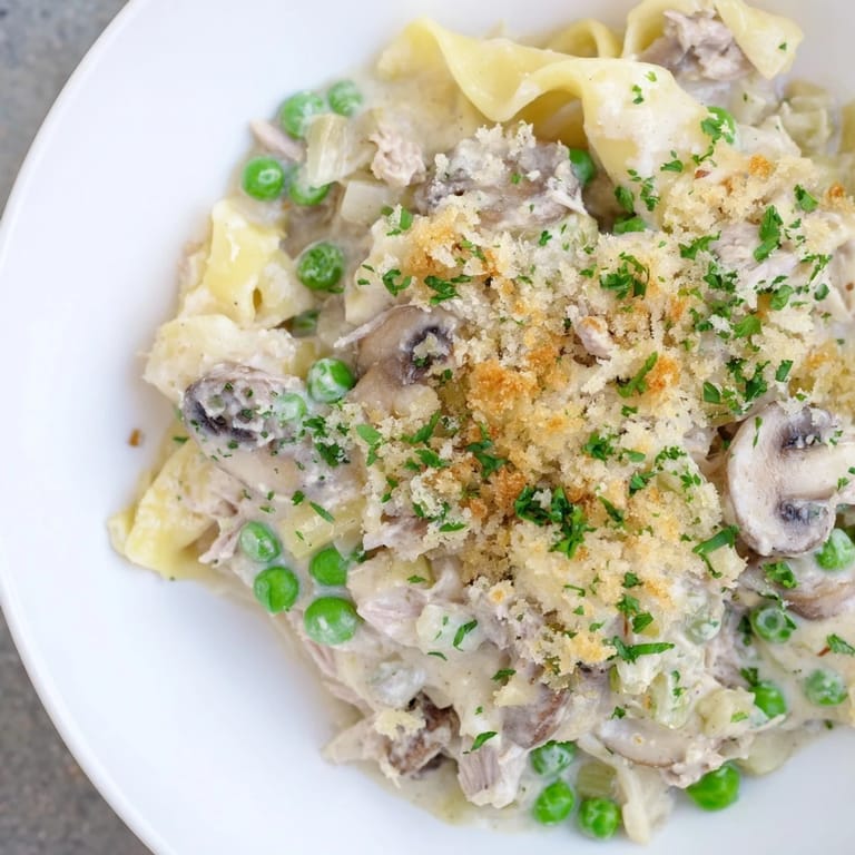 A close-up shot of the flavorful tuna noodle casserole 2.0 bubbling beneath a crispy parmesan topping.