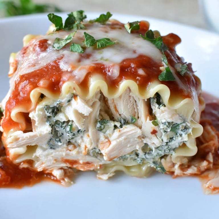 Twisted pasta noodles hold a savory chicken and spinach filling, topped with golden cheese and fresh parsley garnish.