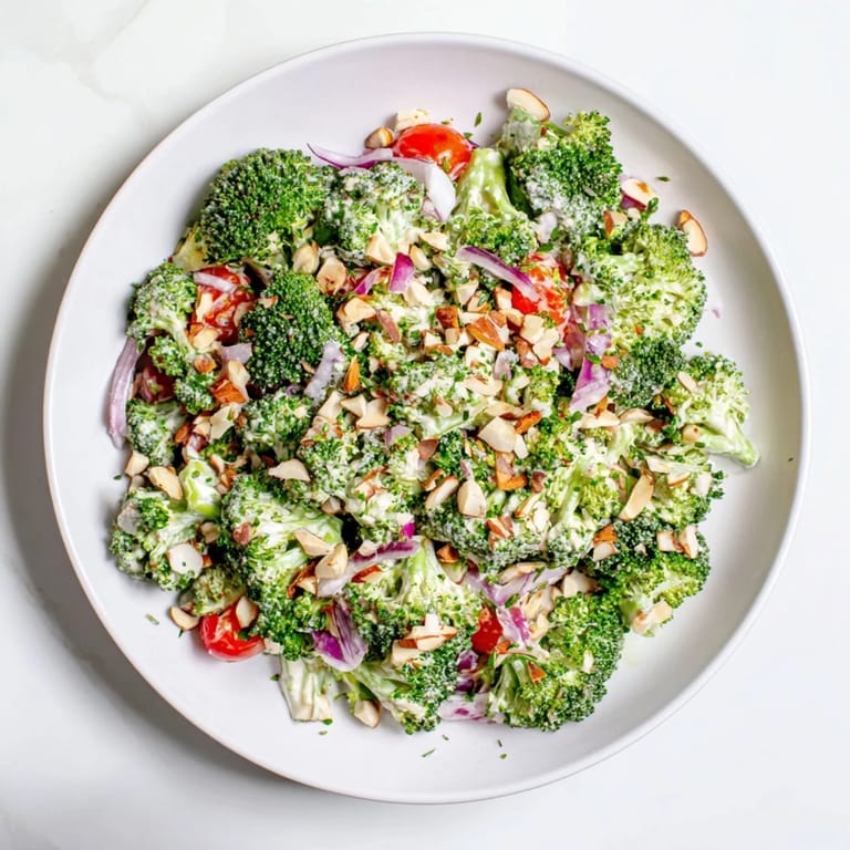 Fresh Garlic Parmesan Broccoli Salad tossed in a tangy dressing, garnished with slivered almonds and extra grated Parmesan.